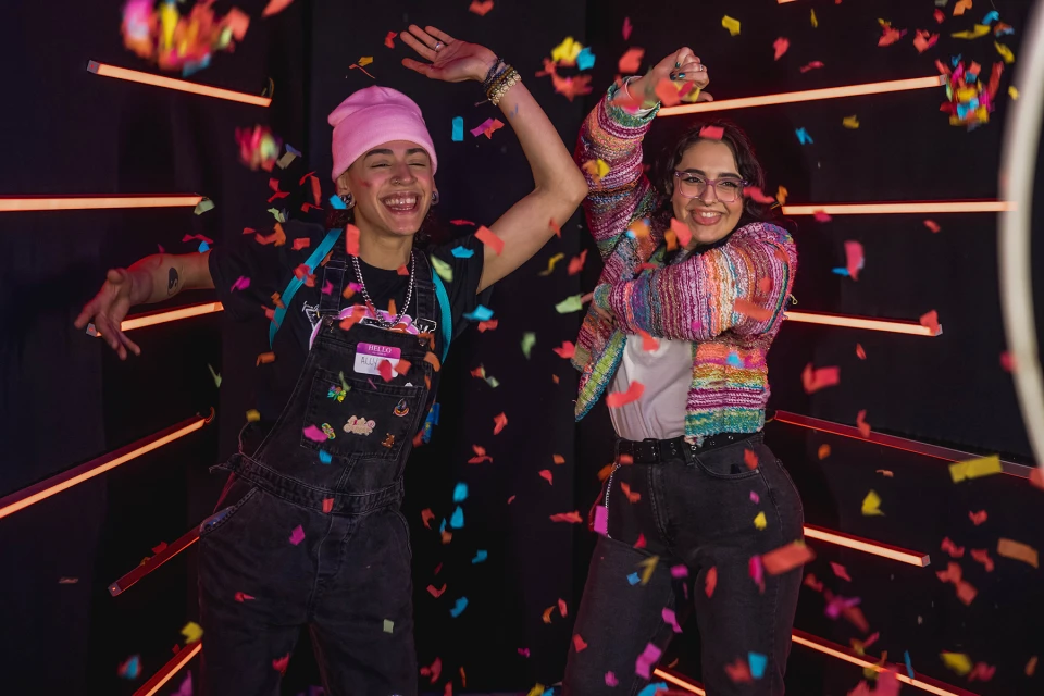 Medewerkers poseren lachend met props voor een kleurrijke LED-achtergrond en photobooth.