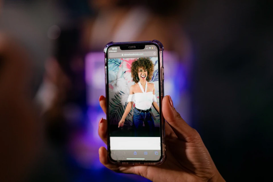 Persoon bekijkt net gemaakte photobooth-foto op een smartphone met sfeervolle verlichting.