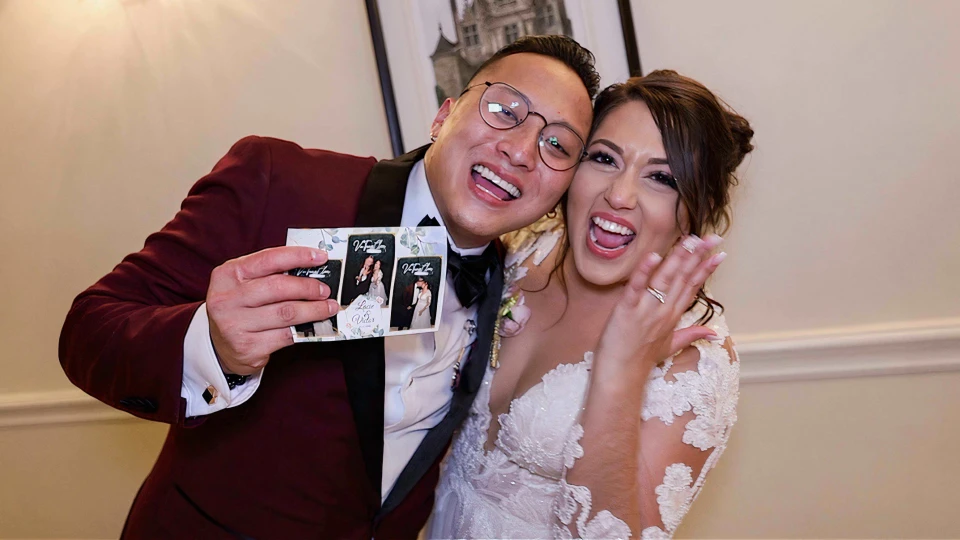 Bruid en bruidegom lachen met hun photobooth-foto tijdens een vrolijk huwelijksfeest.